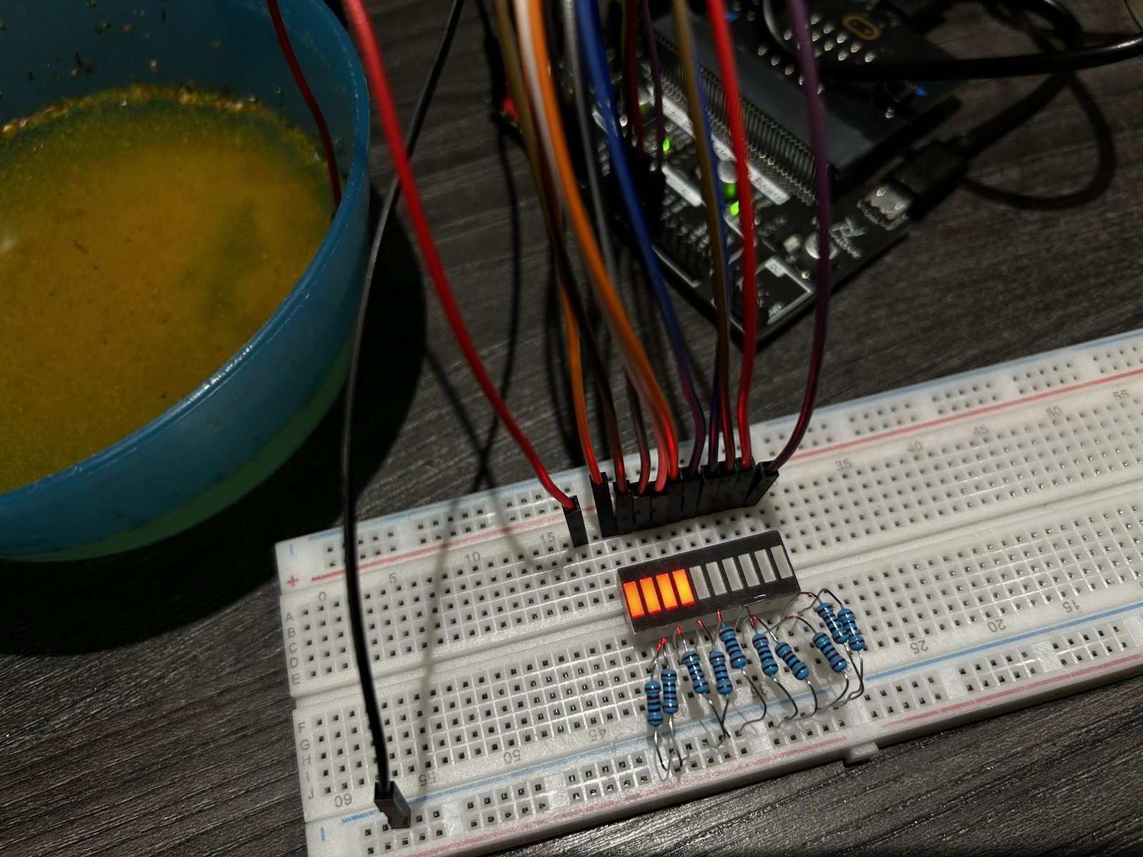 The LED bar graph wired up next to a bowl of coloured liquid, simulating the pH-paper water-purity measurement.