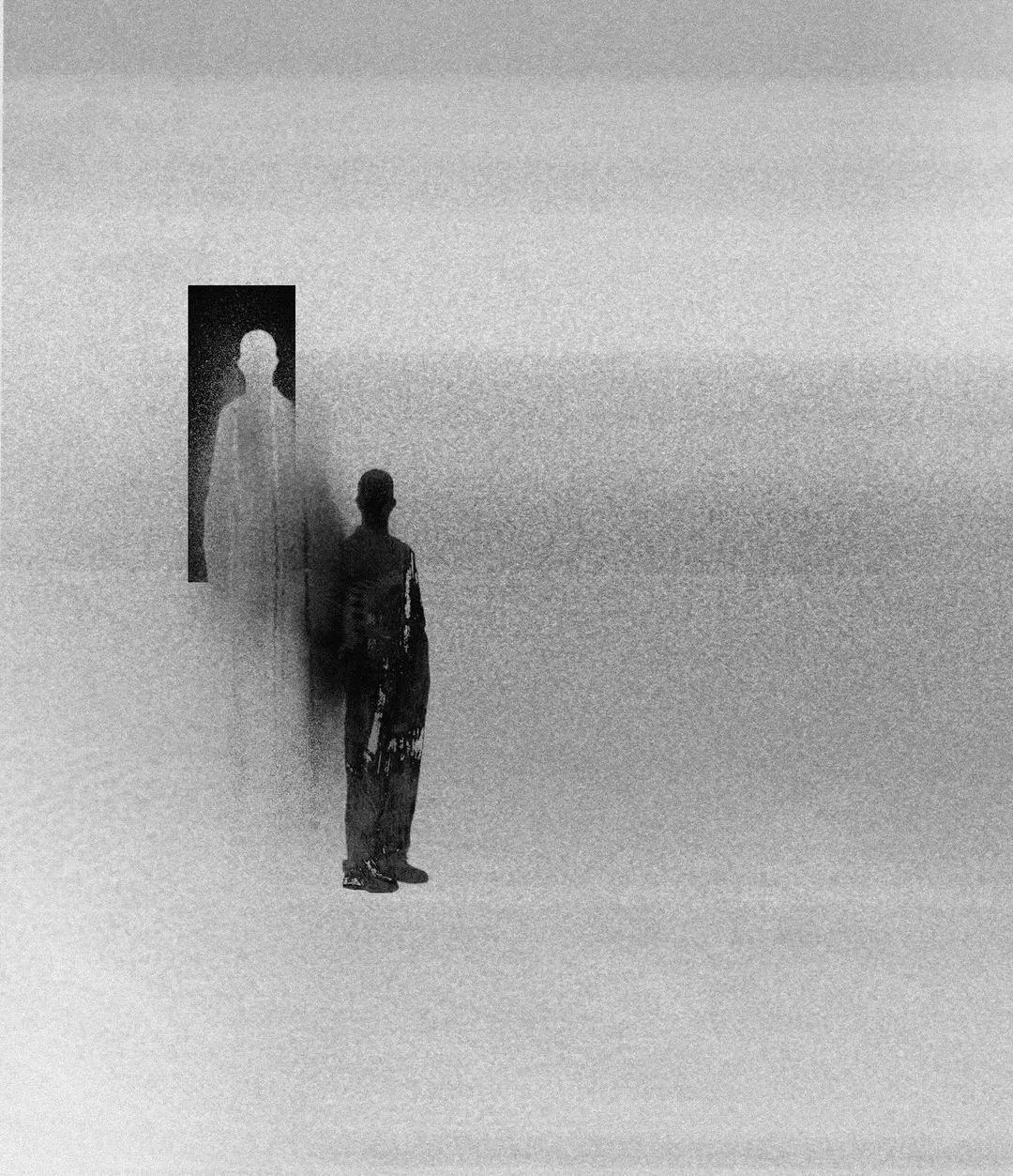 A grainy, high-contrast photo of a figure standing beside a faint, ghostlike double of themselves against a blank wall.